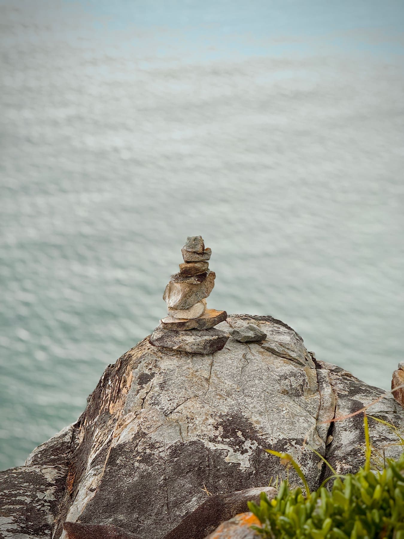 A small stack of stones on a granite boulder above the sea