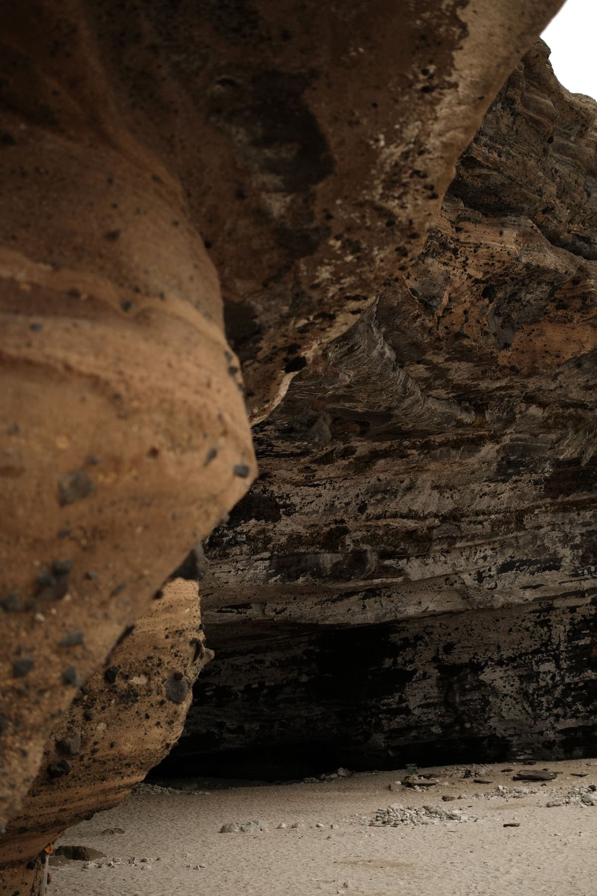 The mouth of a sea cave opening onto white sand