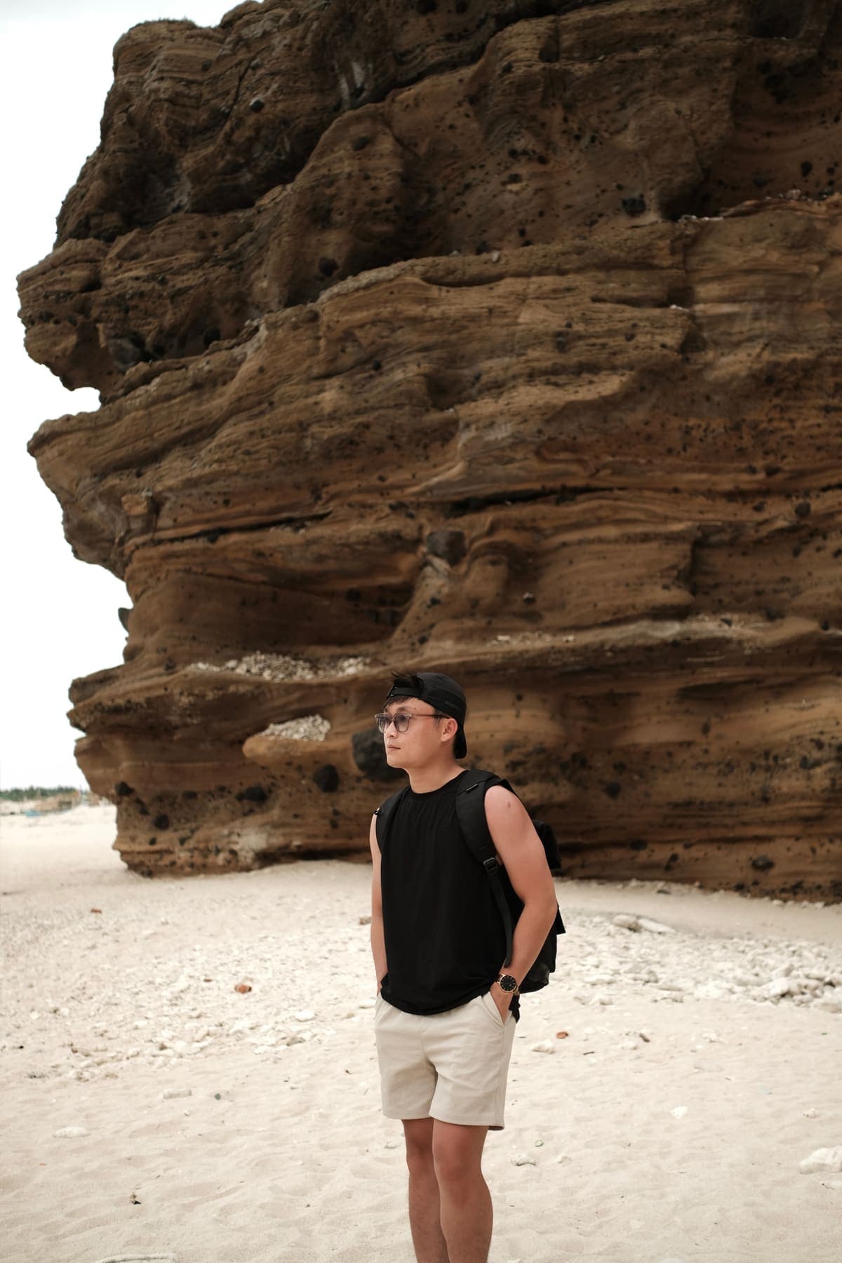 A man in sunglasses on the beach in front of layered cliffs