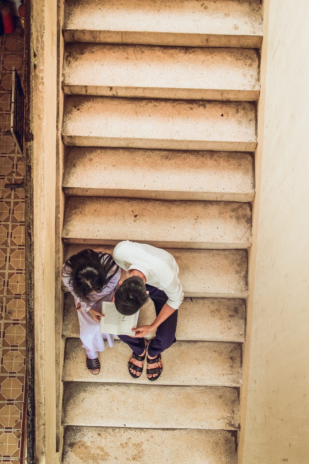 Two students sitting on a worn staircase, seen from directly above