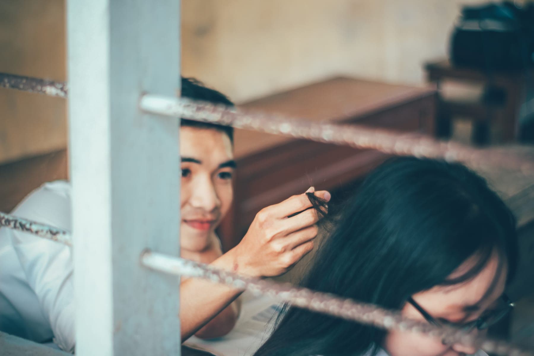 A boy smiling through window bars at a girl in glasses