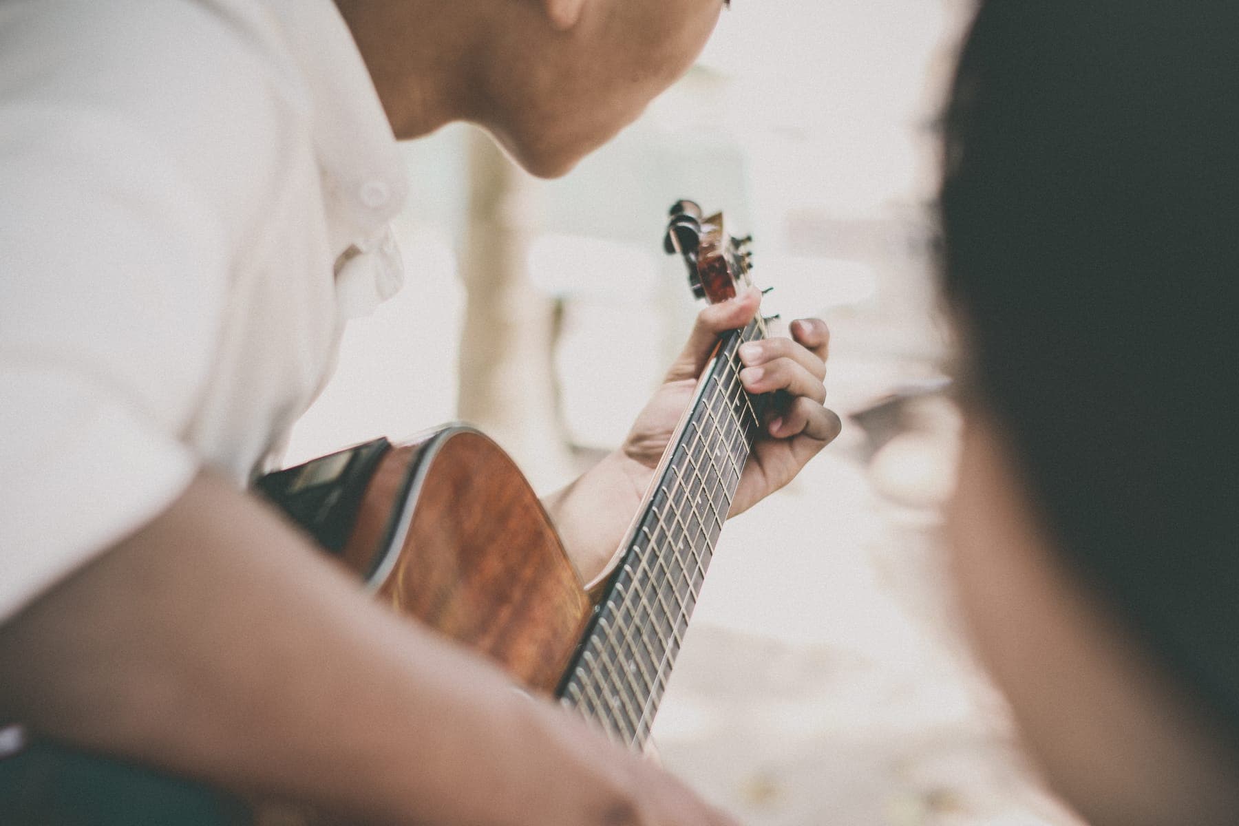 A boy in a white shirt playing an acoustic guitar
