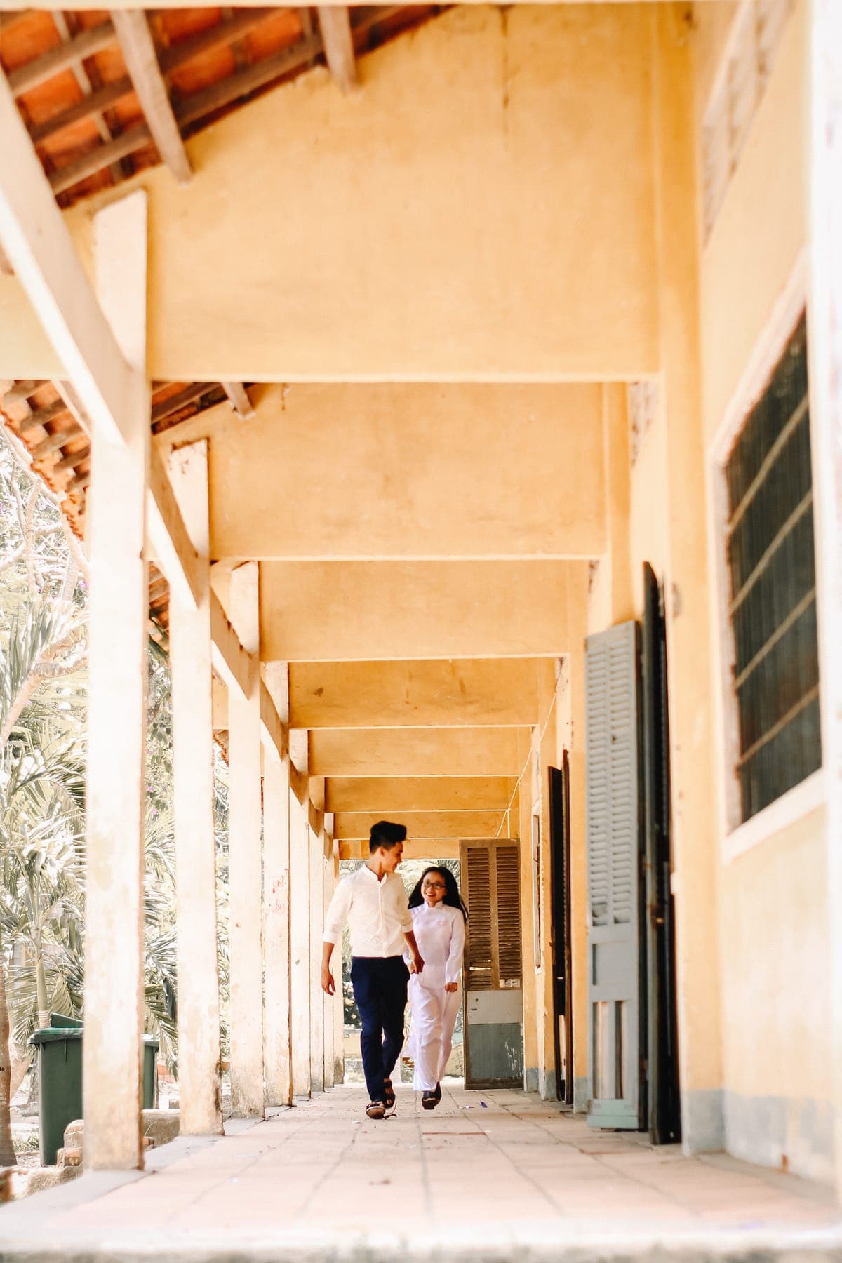 Two students walking down a long, sunlit school corridor