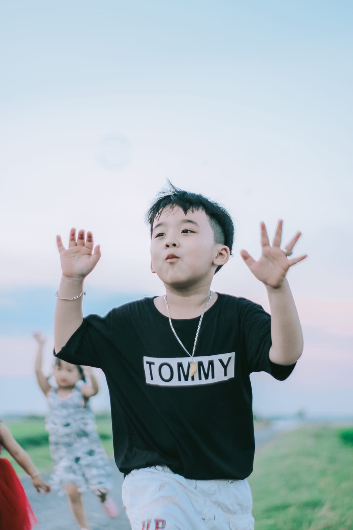 A boy in a black T-shirt reaching up to catch soap bubbles