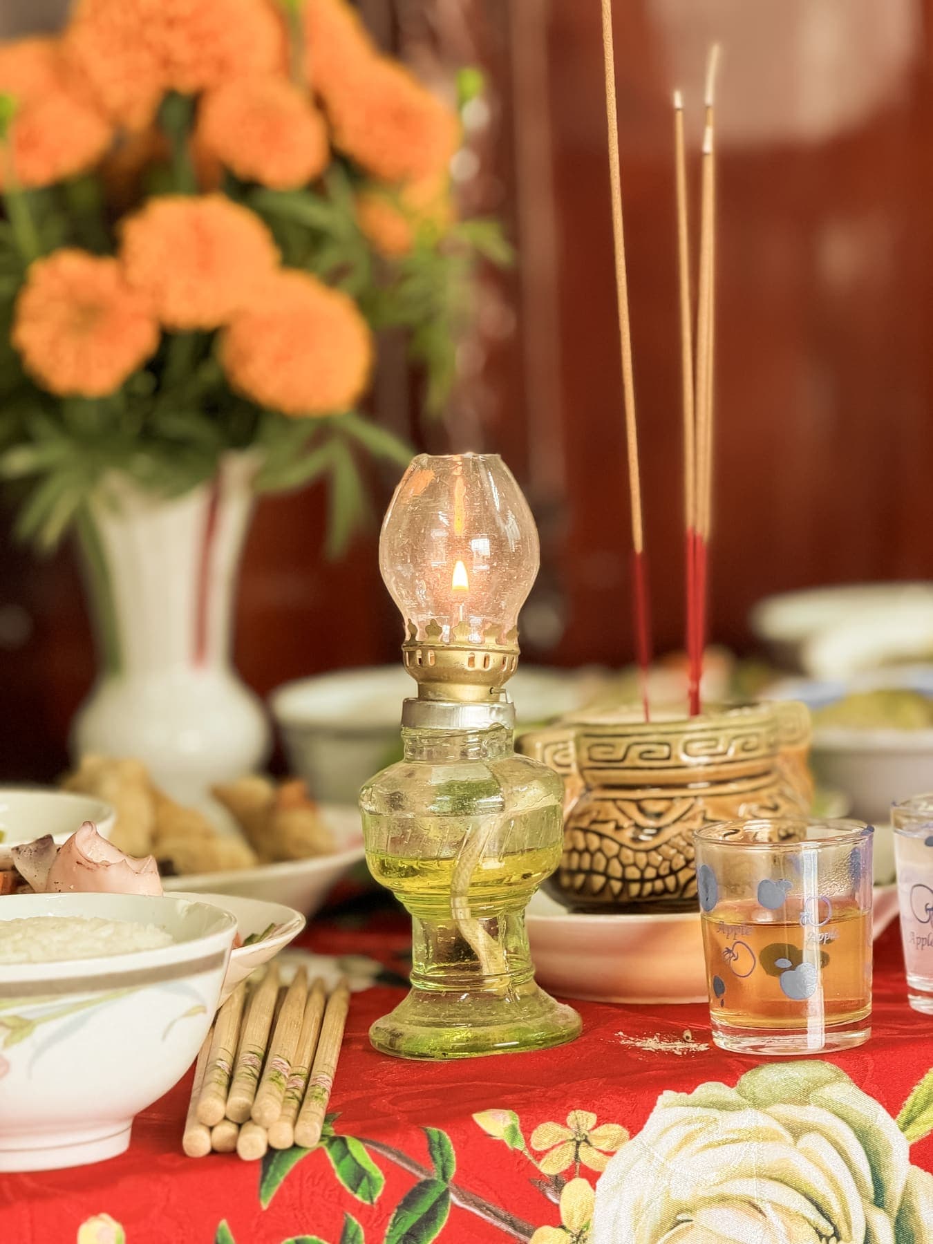 Marigolds, an oil lamp and burning incense on the altar table
