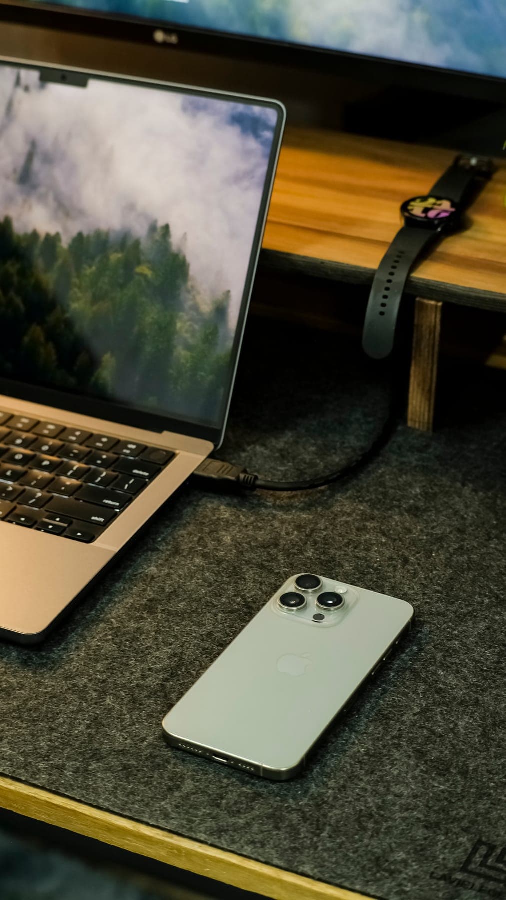 Close-up of a laptop keyboard and a phone on a felt desk mat