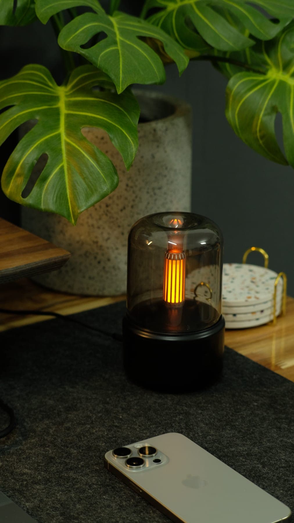 A small glowing lantern on the desk next to a coaster